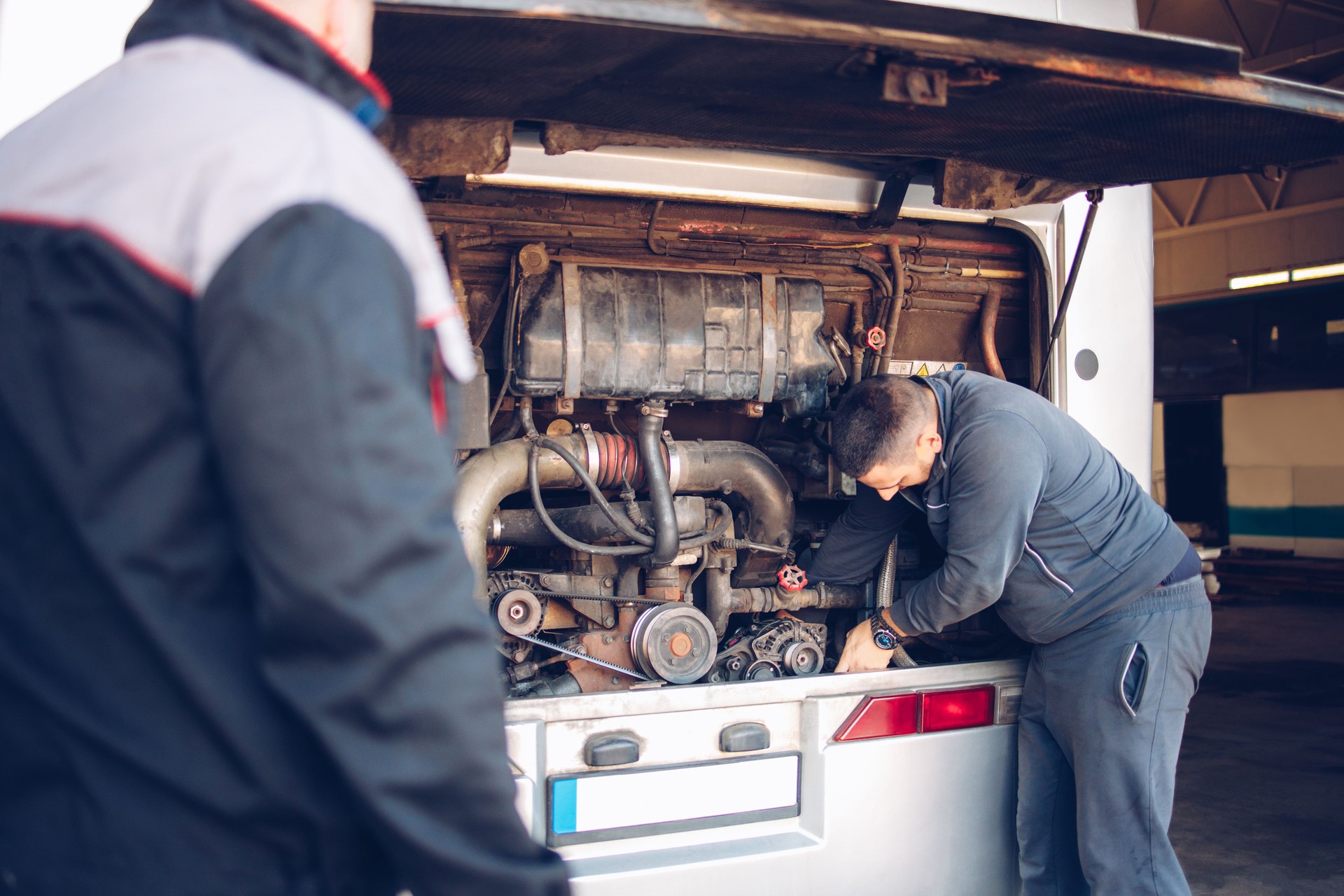 Male mechanic and assistant working on a bus motor