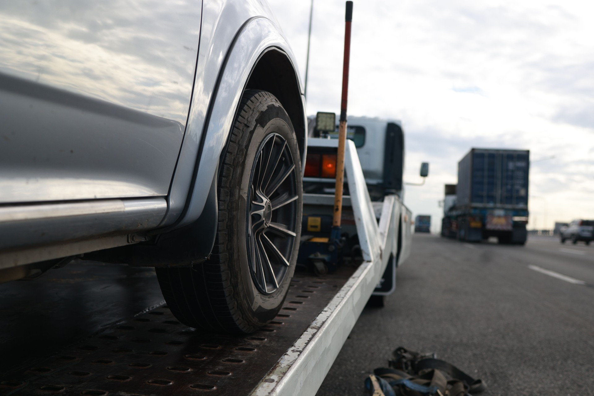 Loading a car onto a tow truck. A broken-down vehicle on the highway receives expert care from a tow truck, getting back on track for a safe and hassle-free journey.